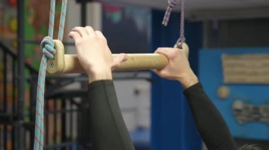 Beyaz bir adam trapezde barfiks çekiyor. Tırmanma duvarından önce ısınma.