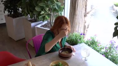 Kafeteryada çorba içen mutlu beyaz kadın.