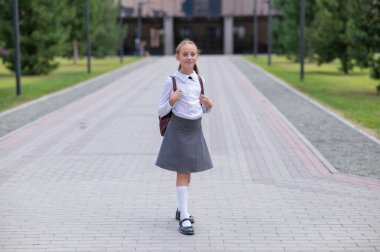 Beyaz kız öğrenci portresi. Üniformalı ve sırt çantalı.