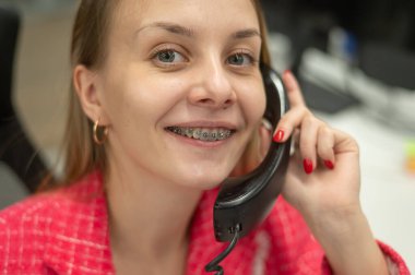 Diş teli takan iş kadını telefonda konuşuyor.