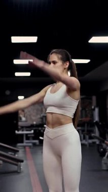 Beyaz kadın spor salonunda kol sallıyor.