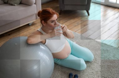 Hamile kadın spor yaptıktan sonra su içer.