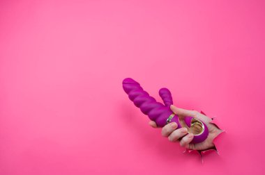 Pembe kağıttan yapılmış pembe seks oyuncağıyla dışarı çıkmış bir kadın eli. Boşluğu kopyala