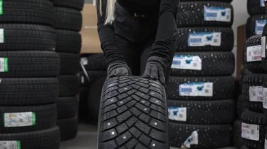 Bir satıcı bir mağazada çivili bir kış lastiği takıyor.