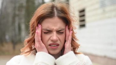 Beyaz kadın sonbaharda yürürken baş ağrısı çekiyor.