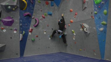 Beyaz adam tırmanma duvarında eğitim görüyor.