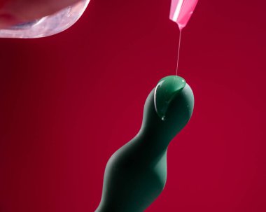 Pembe arka planda yeşil anal boncuklara yağ dökülüyor.