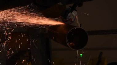 Bir kaynakçı metal bir boruyu keser.