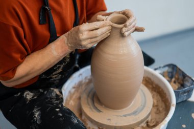 Çömlekçi elleriyle çömlekçi çarkında seramik vazo yaparken.