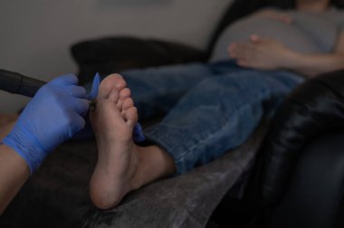 Güzellik salonunda hırdavat pedikür yapan hamile bir kadın.