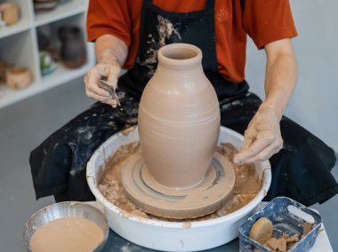 Çömlekçi elleriyle çömlekçi çarkında seramik vazo yaparken.