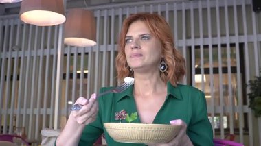 Beyaz kadın yazın kafede salata yiyor.