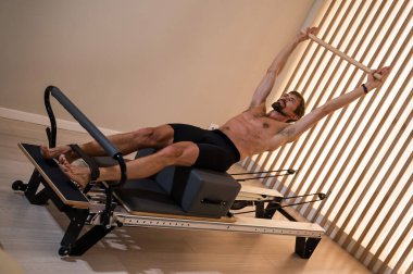 Reformcu üzerinde pilates yapan bir adam.