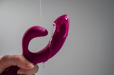 Lube pouring on pink dildo on white background