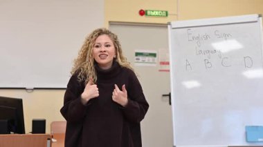 Beyaz kadın üniversitede işaret dili öğretiyor.