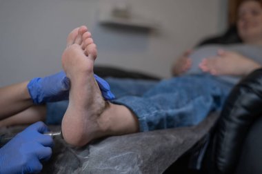 Güzellik salonunda hırdavat pedikür yapan hamile bir kadın.