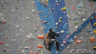 Beyaz adam tırmanma duvarında eğitim görüyor.