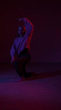 A young woman dances contemporary dances in blue and red light. Long exposure. Vertical video