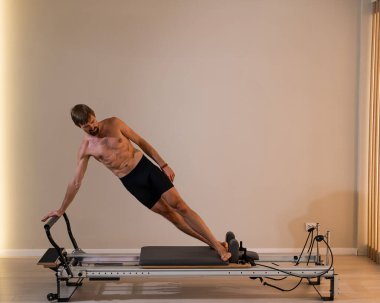 Reformcu üzerinde pilates yapan bir adam.