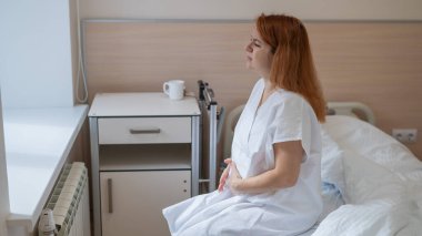 Mutsuz hamile bir kadın hastane odasındaki kanepede oturuyor.