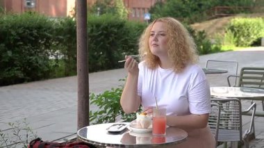 Caddedeki kafede kek yiyen şişman beyaz kadın.
