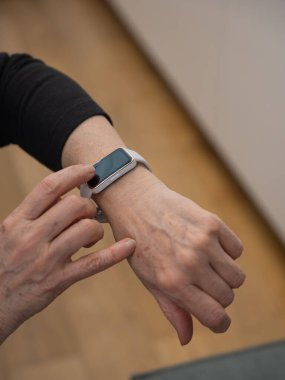 Kafkasyalı yaşlı bir kadın akıllı saate bakıyor. Ellerin yakın çekimi