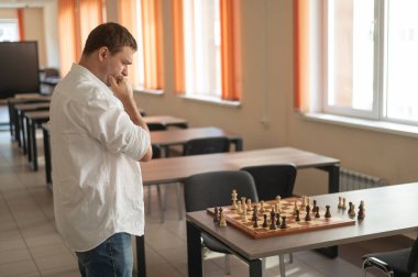 Beyaz adam satranç hamlesi düşünüyor.