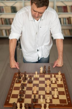 Beyaz adam satranç hamlesi düşünüyor.