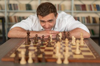 Beyaz adam satranç hamlesi düşünüyor.