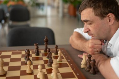 Beyaz adam satranç hamlesi düşünüyor.