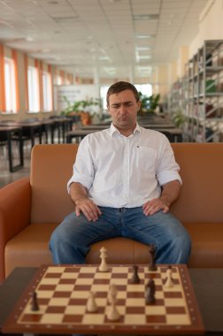 Beyaz adam satranç hamlesi düşünüyor.