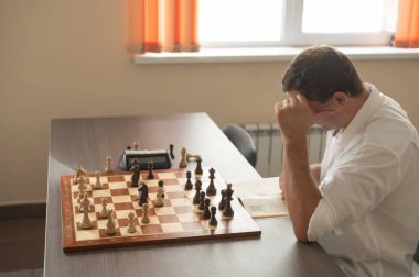 Beyaz adam satranç hamlesi düşünüyor.