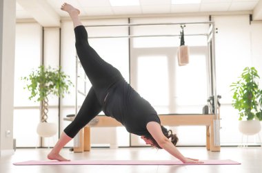 Şişman kadın stüdyoda yoga yapıyor.