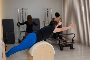 Pilates yapan üç kadın ve pilates yapan bir fıçı.