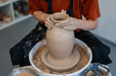 Çömlekçi elleriyle çömlekçi çarkında seramik vazo yaparken.