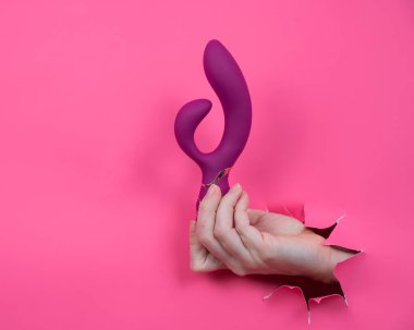 Pembe kağıttan yapılmış ahududulu seks oyuncağıyla takılan bir kadın eli.