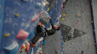 Beyaz adam tırmanma duvarında eğitim görüyor.