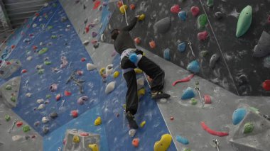 Beyaz adam tırmanma duvarında eğitim görüyor.