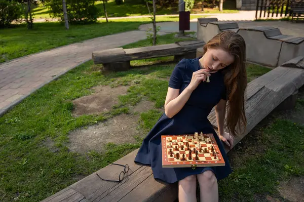Beyaz kadın dışarıda satranç oynuyor.