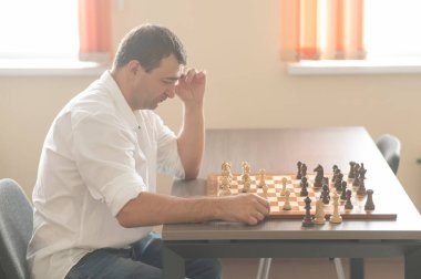 Beyaz adam satranç hamlesi düşünüyor.