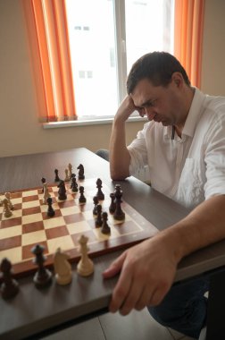 Beyaz adam satranç hamlesi düşünüyor.