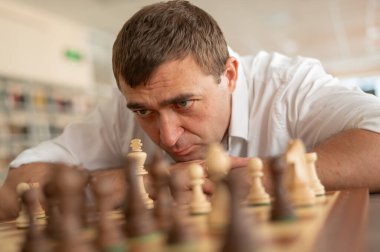 Beyaz adam satranç hamlesi düşünüyor.