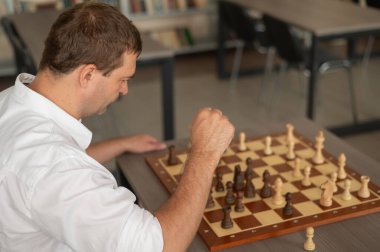 Beyaz adam satranç hamlesi düşünüyor.