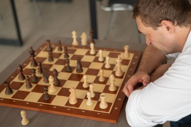 Beyaz adam satranç hamlesi düşünüyor.