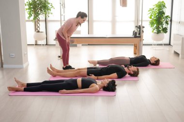 İki kadın ve bir erkek stüdyoda yoga yapıyorlar.