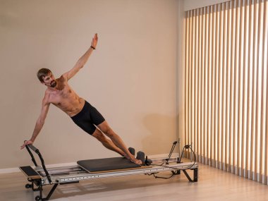 Reformcu üzerinde pilates yapan bir adam.