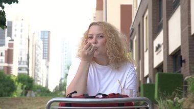 Caddedeki kafede kek yiyen şişman beyaz kadın.