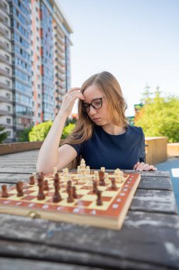 Beyaz kadın dışarıda satranç oynuyor. Dikey fotoğraf