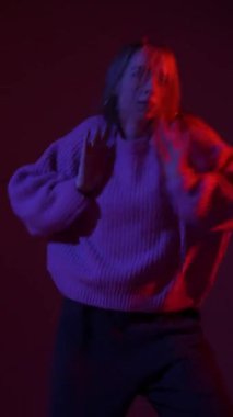 A young woman dances contemporary dances in blue and red light. Long exposure. Vertical video