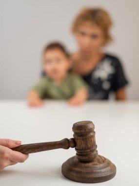 Hakim, elinde çocuk tutan yaşlı bir kadının arka planına vuruyor.